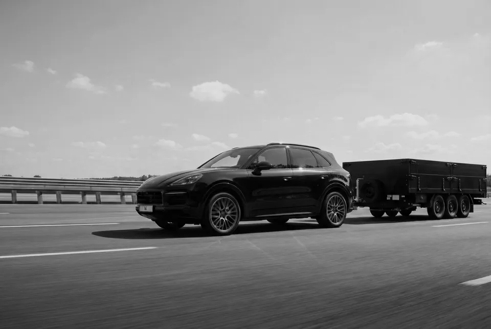 Zwart-witfoto van een auto die een BW-plateauwagen trekt op de autosnelweg.